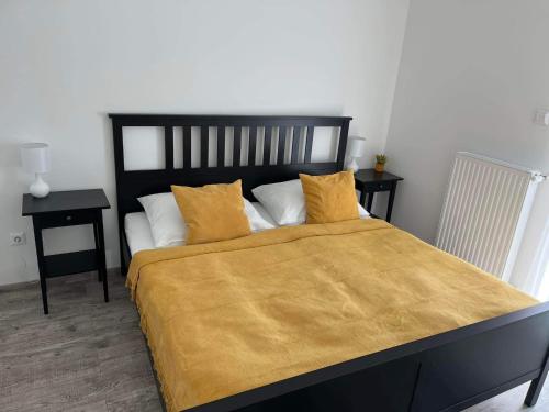 a bedroom with a large bed with a yellow blanket at ADA Apartman Sopron in Sopron