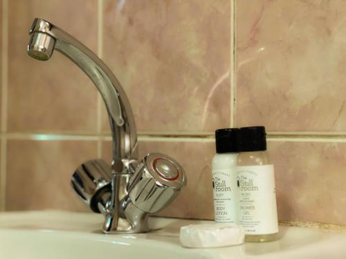 a sink with a faucet and a bottle of soap at Mopani Lodge Victoria Falls in Victoria Falls