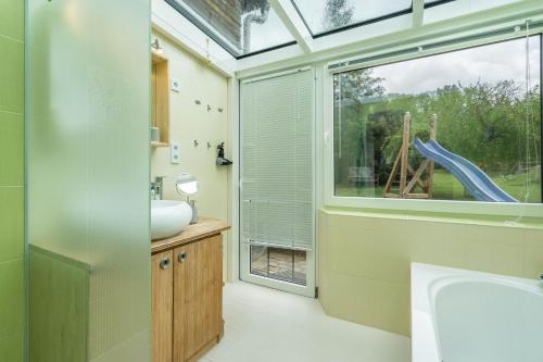 a bathroom with a sink and a window with a slide at Chalet Kunterbunt in Langenwetzendorf
