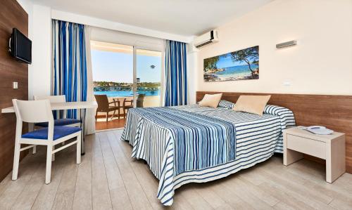 una camera d'albergo con letto, tavolo e sedie di Globales Verdemar a Santa Ponsa