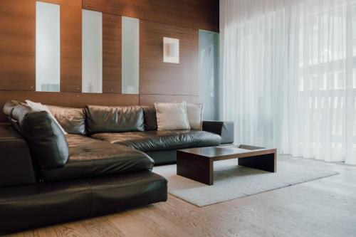 a living room with a leather couch and a coffee table at Residence Hotel Alpinum in Campo Tures