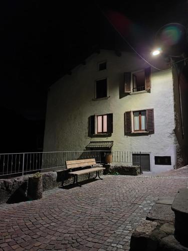 a bench in front of a building at night at Appartamento centro storico in Ornica