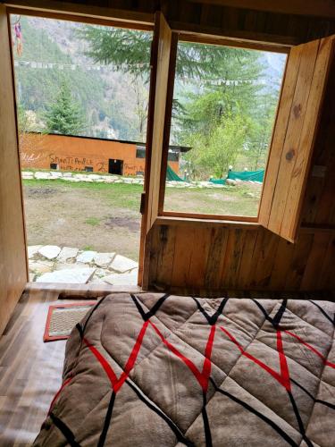 a bed in a room with a window at Shanti People Huts & Camp in Kasol