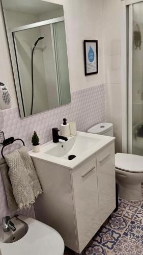 a bathroom with a sink and a toilet and a mirror at Canet playa y centro con free wifi in Canet de Mar