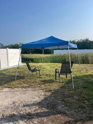 two chairs and a blue tent in a field at RV SITE FOR RENT BY GLAMPERS CAMP 30AMP FULL HOOKUP in Port Charlotte