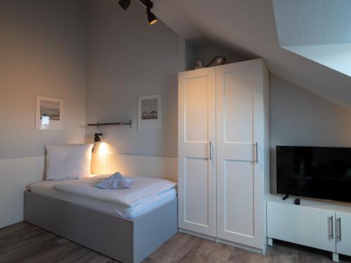 a small bedroom with a bed and a white cabinet at Appartementhaus Westerloog 20 in Spiekeroog