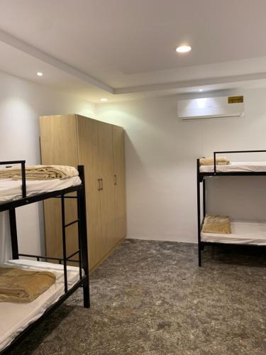 a room with three bunk beds and a cabinet at The Traveler Hostel in Riyadh