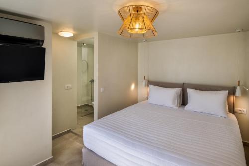 a bedroom with a bed with a television and a chandelier at Hillside Elegance in Fira