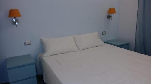 a bedroom with a white bed with two blue tables at Casa Per 2 in Porto Santo Stefano