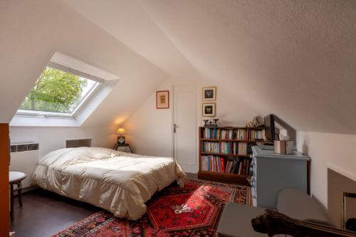 1 dormitorio en el ático con cama y ventana en Ty Clafout, en Saint-Nolff