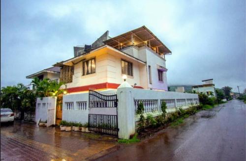 a house with a white fence on a street at LAUGHTALE VILLA 4Bhk Swimming Pool in Lonavala