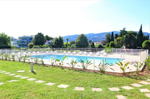 - une grande piscine avec des chaises dans un complexe dans l'établissement Appartement 9 en Duplex- LES SUITES DE ROBINSON - Résidence avec piscine en bord de Siagne, à Mandelieu-La-Napoule, à Mandelieu-la-Napoule