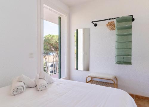 a white bedroom with a bed and a window at Apartamentos CASA MAREA Calella Palafrugell con Parking in Calella de Palafrugell