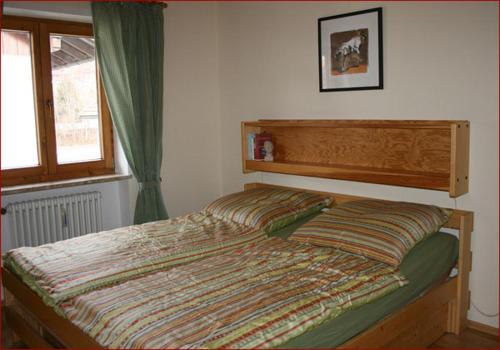 Schlafzimmer mit einem Bett mit einem Kopfteil aus Holz und einem Fenster in der Unterkunft Ferienwohnung Liedloff in Bad Hindelang