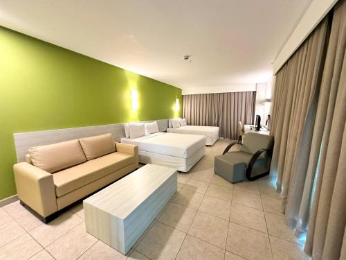 una sala de estar con muebles blancos y una pared verde. en Enotel Porto de Galinhas All Inclusive, en Porto de Galinhas