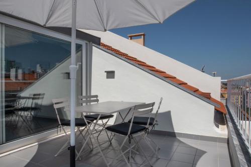 a table and chairs on a balcony with an umbrella at Oscar Concept Apartments in Lisbon