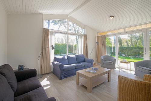 ein Wohnzimmer mit einem blauen Sofa und einem Tisch in der Unterkunft Vakantiehuis Duynloper - Julianadorp aan Zee in Julianadorp