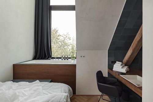 a bedroom with a tub and a bed and a desk at Lukas Kapeller Hotel und Restaurant in Steyr