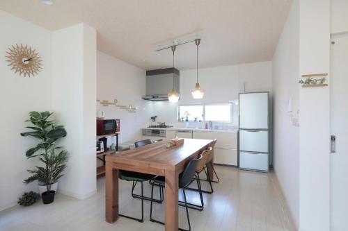 a kitchen with a wooden table and a refrigerator at MT名嘉真 in Inbu