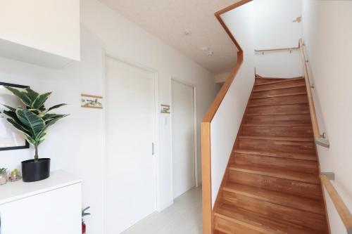 a staircase in a home with white walls and wooden floors at MT名嘉真 in Inbu