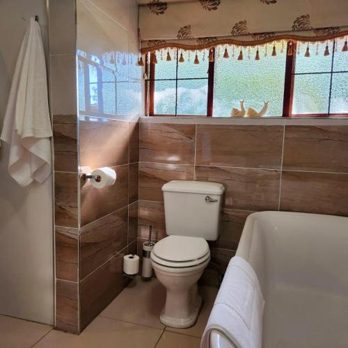 a bathroom with a toilet and a bath tub at Orange gecko cottage in Phalaborwa