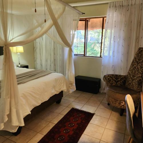 a bedroom with a bed and a chair and a window at Orange gecko cottage in Phalaborwa
