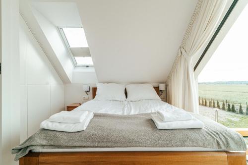 a bedroom with a bed with white sheets and a window at Sea & Sun in Wierzchucino