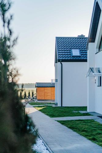 a white house with a orange garage in the distance at Sea & Sun in Wierzchucino