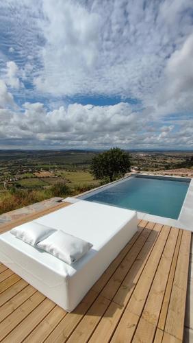 a white bed sitting on a deck next to a swimming pool at Casa Alquerque in Monsaraz