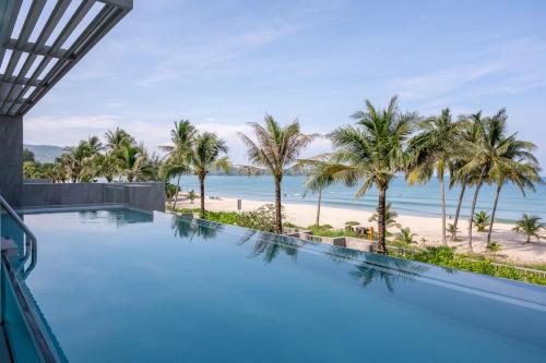 an infinity pool with a view of the beach and palm trees at Beachfront Residences - Stunning Sea and Lake View in Bang Tao Beach