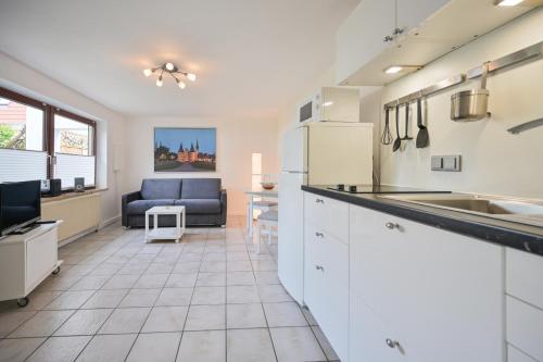 une cuisine avec des armoires blanches et un canapé dans une pièce dans l'établissement FeWo Breuker, à Kellenhusen