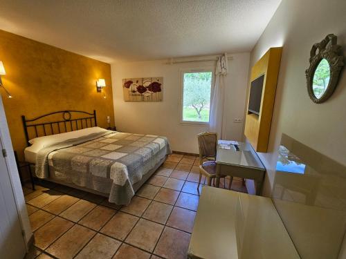 1 dormitorio con cama, escritorio y ventana en Les Sables d'Ocre & SPA, en Roussillon