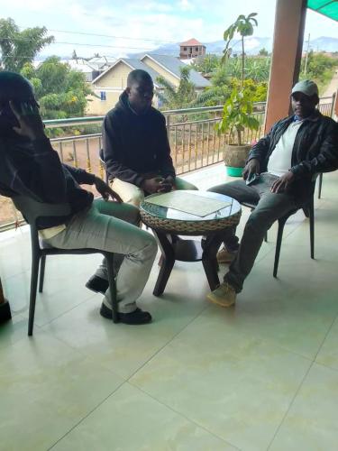 Rwenzori Mountains Safari Lodge في كاسيزي: مجموعة من ثلاثة رجال يجلسون على الشرفة