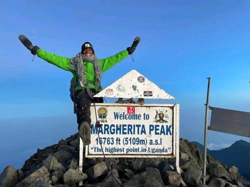 una persona de pie en la cima de un cartel en una montaña en Rwenzori Mountains Safari Lodge, en Kasese