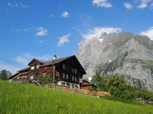 een huis op een heuvel met een berg op de achtergrond bij Dorengaden, 2-3 Bett Wohnung an ruhiger Lage mit Solarstrom in Grindelwald