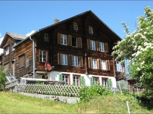 een groot houten huis met een hek ervoor bij Dorengaden, 2-3 Bett Wohnung an ruhiger Lage mit Solarstrom in Grindelwald