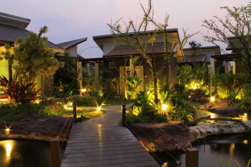 a garden with a wooden walkway in front of a house at Saabpaiboon Grand Resort in Ban Talat