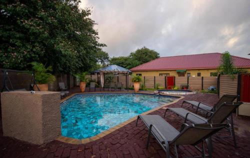 uma piscina com cadeiras e uma casa em Happy Holiday Backpackers em Victoria Falls