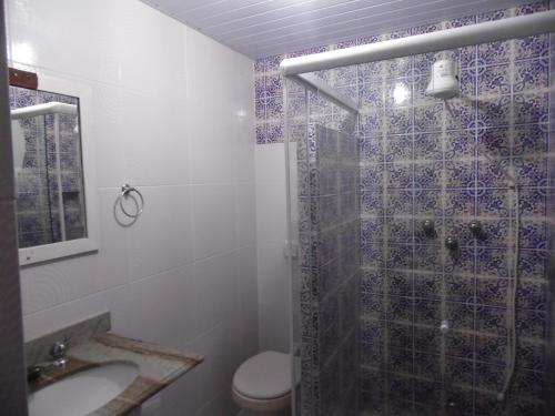 uma casa de banho com um chuveiro, um WC e um lavatório. em Pousada Casa dos Sonhos em Rio das Ostras