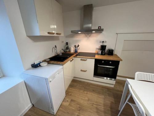 a kitchen with white cabinets and a black stove at Charmante maison à Evran proche Dinan et St Malo. in Évran