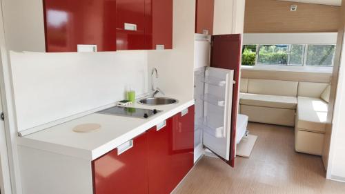 a kitchen with red and white cabinets and a sink at One bedroom bungalow with shared pool and wifi at Lizzano 6 km away from the beach in Lizzano