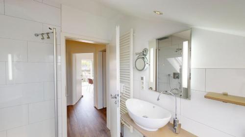 a white bathroom with a sink and a mirror at 54° Nord Wohnung 6 in Grömitz