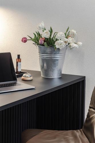 a bucket of flowers sitting on a desk with a laptop at Lukas Kapeller Hotel und Restaurant in Steyr