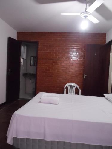 a bedroom with a white bed with a brick wall at Pousada Casa dos Sonhos in Rio das Ostras