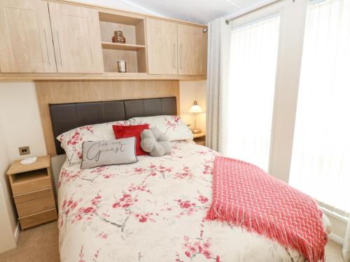 a bedroom with a bed with a red and white comforter at Plot 32 in Carlisle