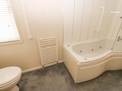 a white bathroom with a toilet and a bath tub at Plot 32 in Carlisle