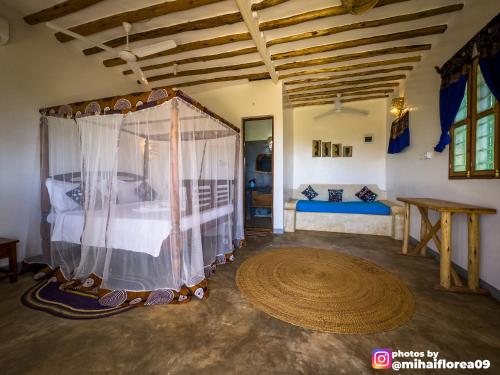 a bedroom with a bed and a table in a room at Tofauti Inn in Makunduchi