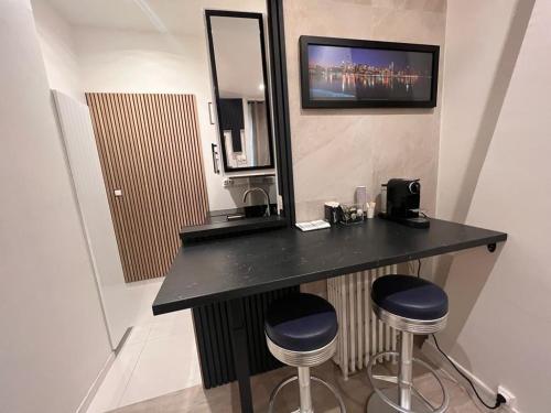 une salle de bains avec un comptoir noir et deux tabourets dans l'établissement 269 Suite Pereire - Superb apartment in Paris, à Paris