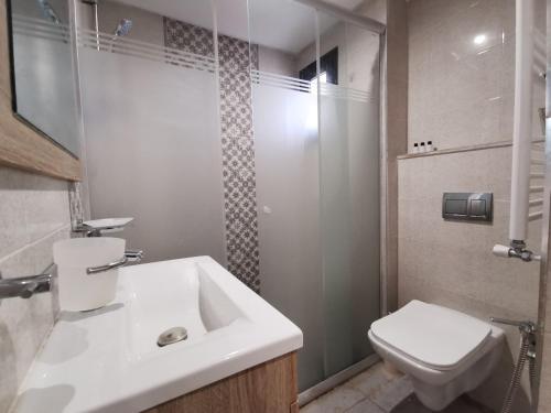 La salle de bains est pourvue d'un lavabo blanc et de toilettes. dans l'établissement Appartement RDC pieds dans l'eau parking privée, à Hammam Sousse