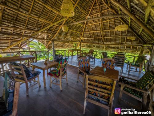 a restaurant with tables and chairs in a straw roof at Tofauti Inn in Makunduchi